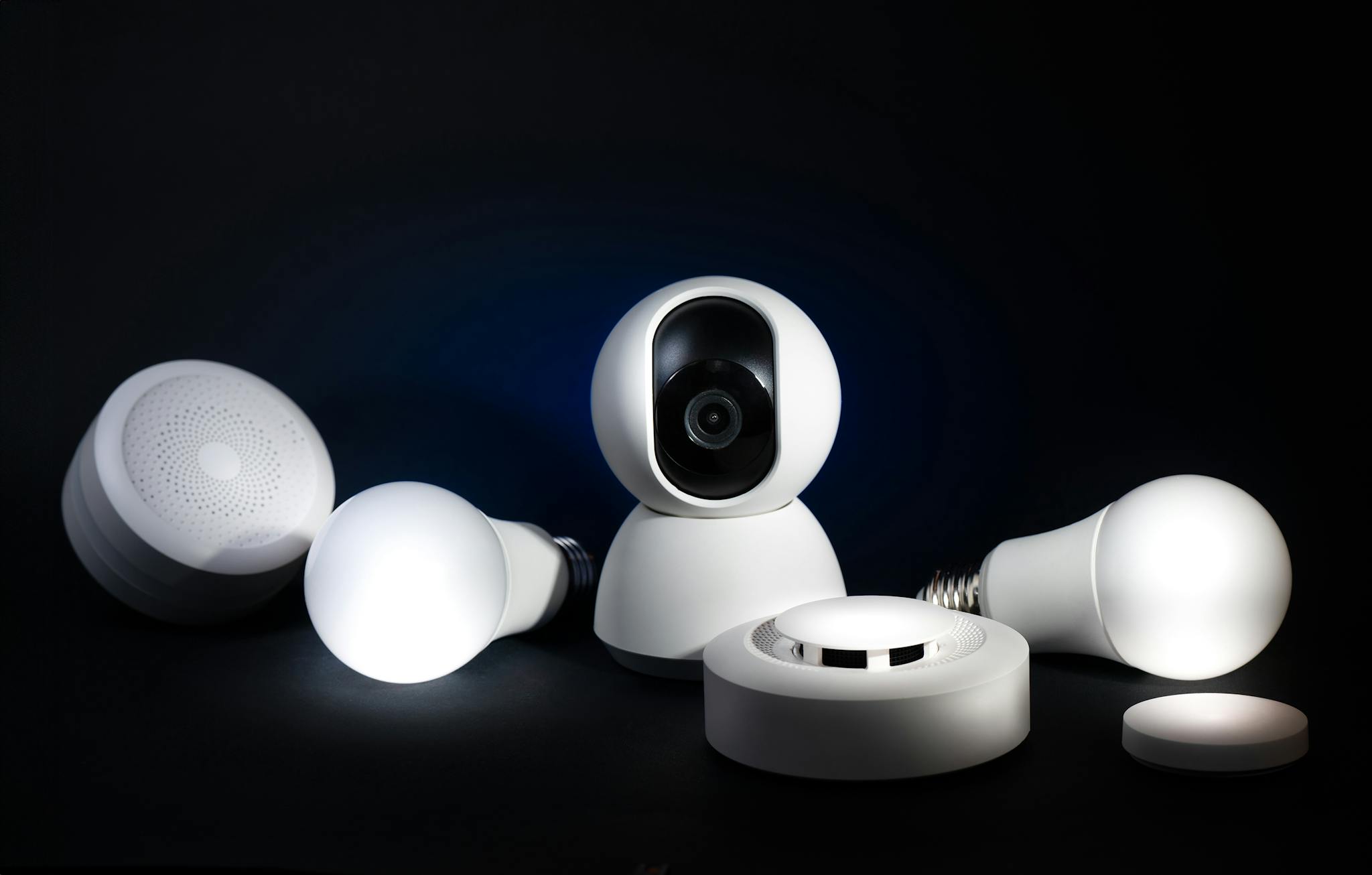 A collection of smart home devices, including bulbs and security cameras, on a dark background.