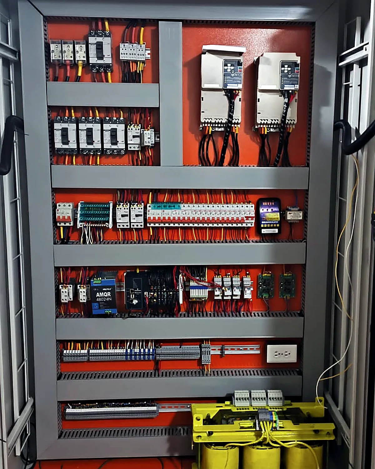 Interior de un tablero eléctrico de baja tensión de SOLINTECK, con placa de montaje naranja, interruptores de caja moldeada, variadores de velocidad, borneras y transformador seco de aislamiento