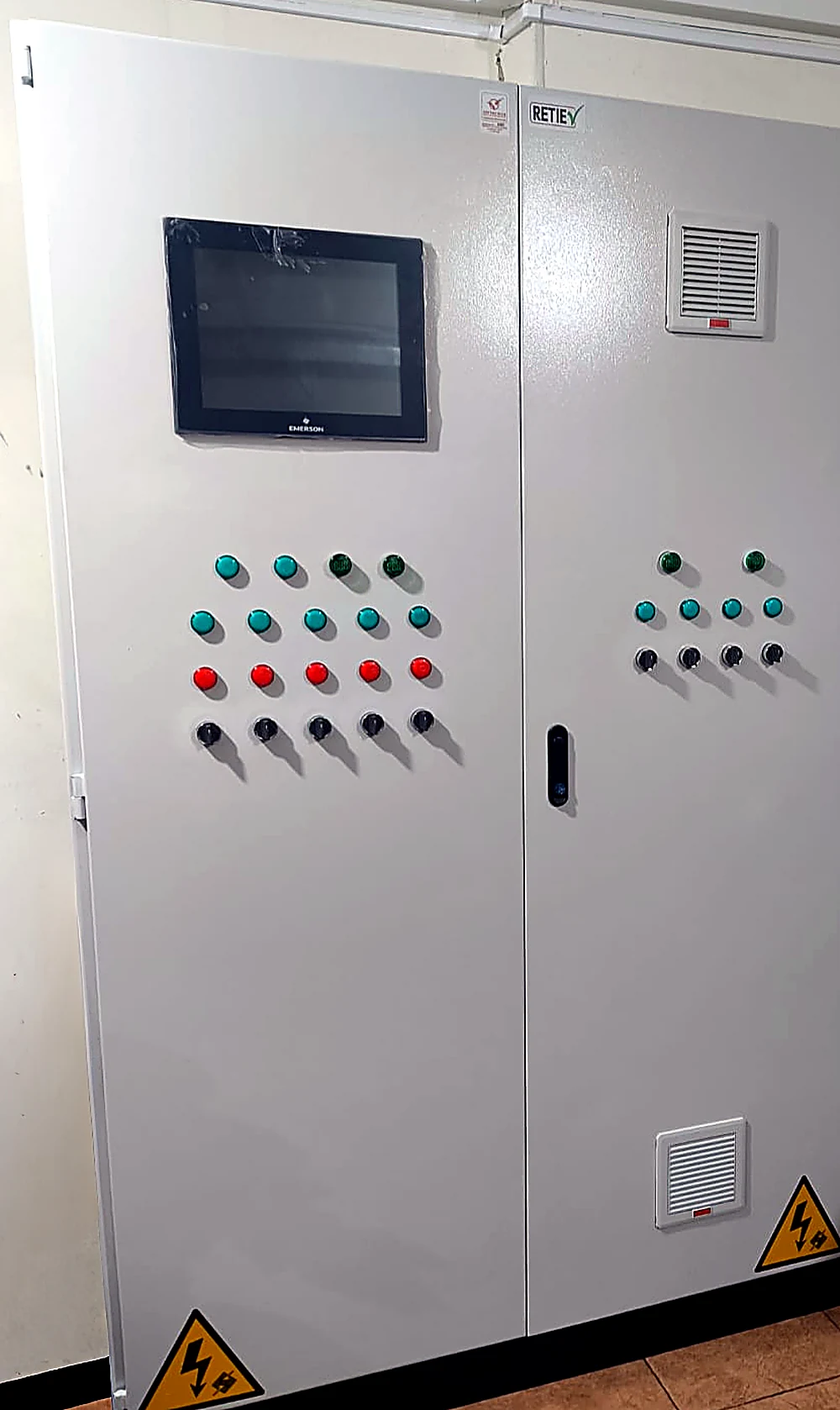 Frente de un tablero eléctrico de baja tensión fabricado por SOLINTECK, con marquilla RETIE sobre la puerta, pantalla HMI, pulsadores y pilotos de mando y rejillas de ventilación filtrada